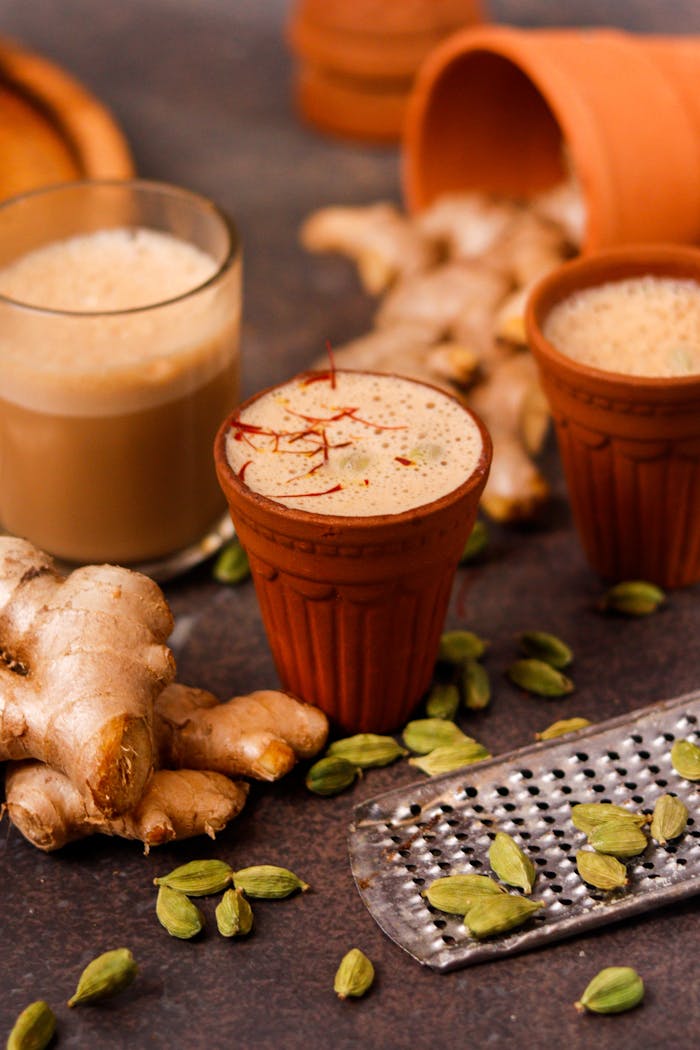 heros-img Close-up of masala chai in clay cups surrounded by ginger and cardamom for a rustic look.